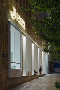 夜晚經典店面，磚牆立面，三人坐在外頭長椅上，享受寧靜氛圍