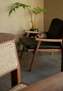 Cozy living area with a wooden chair, tile floor, dining table, and potted plant