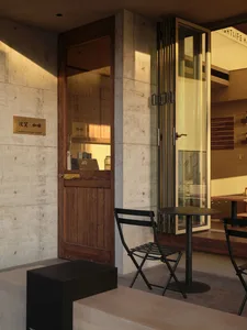Modern restaurant interior with a dining area, kitchen, black chairs, a table, and a couch, featuring a modern and inviting atmosphere
