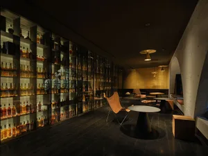 Elegant bar area with a wine selection displayed on shelves behind the counter, comfortable seating, and a sophisticated atmosphere