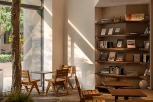Cozy modern living space with a dining table, chairs, bookshelves, and a window, featuring clean lines and neutral tones