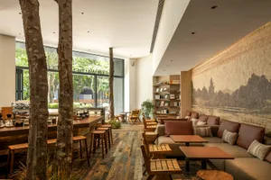A modern restaurant interior with wooden floors, tables, and chairs, creating a warm and inviting atmosphere