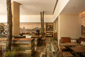 Warm and inviting living area with wooden floors and walls, featuring a kitchen, dining room, and sitting area with chairs and books
