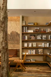 Cozy living area with a bookshelf, chairs, and a couch, featuring numerous books and warm lighting