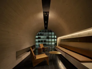 Cozy modern living area with a bench seat, two chairs, and a dining table, well-lit with clean lines and simple shapes