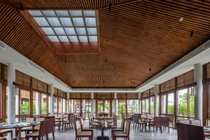 Modern restaurant interior with wooden floors and ceilings, multiple dining tables, and chairs, creating a warm and inviting atmosphere