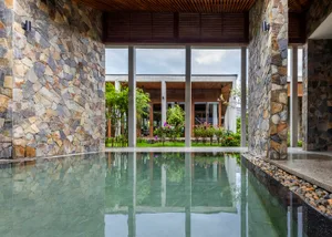 A well-lit pool area with a reflective surface, surrounded by potted plants and a serene ambiance