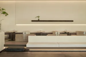 An empty restaurant interior with white walls, tables, chairs, and a potted plant in the center, creating a clean and inviting atmosphere
