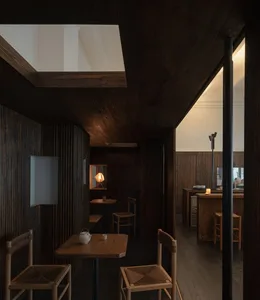Cozy restaurant interior with wooden floors and walls, featuring dining tables and chairs, and a warm atmosphere
