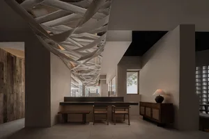 Open living area with white walls, wooden floors, two chairs, a couch, and natural light from a window