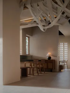 A bright and welcoming living space with a large window, chairs, and a dining table, featuring a comfortable and relaxing atmosphere