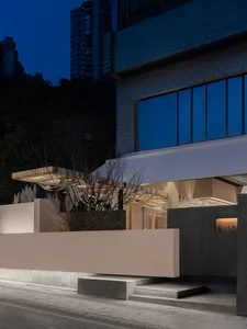 A modern building with a concrete facade and multiple windows, set against a nighttime backdrop with two trees in the foreground