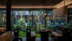 Inviting dining area with a glass table, chairs, and potted plants, set up for a meal