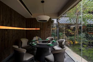 A modern dining area with a round table set for a meal, surrounded by chairs, green plates, and cups, in a space that invites socializing and comfort