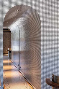 A modern hallway with a silver wall, a tiled floor, and two sinks, creating a functional and modern atmosphere