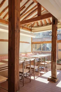 Warm and inviting restaurant interior with wooden beams, tables, and chairs, creating a cozy atmosphere