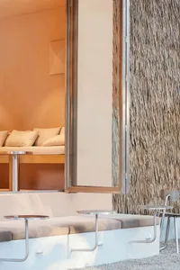 A modern living area with two couches, two chairs, and a dining table, featuring textured wallpaper in a combination of white and brown tones