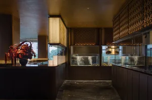 A luxurious restaurant interior with an aquarium centerpiece, surrounded by decorative elements, plants, and bottles, creating a sophisticated ambiance