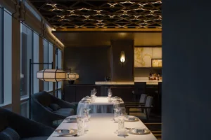 A warm and inviting dining area with a large table, multiple chairs, wine glasses, and bottles, set in a restaurant