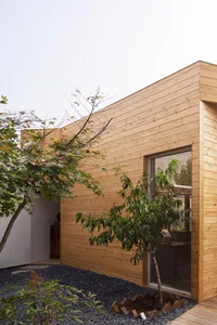A modern wooden house with a large window and a serene atmosphere, surrounded by trees