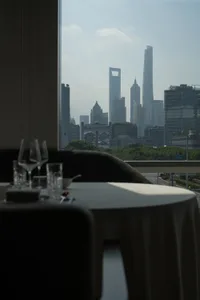 A rooftop dining space with a set table, wine glasses, and a city view from a high vantage point