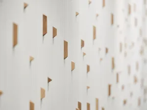 A white wall with wooden triangles attached, creating a geometric pattern with a warm and natural feel