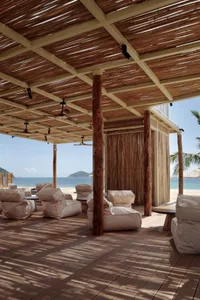 A relaxed outdoor patio area with multiple couches and chairs under a large wooden structure, perfect for socializing or enjoying the outdoors