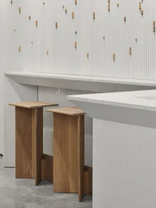 A kitchen area with three wooden stools placed under a marble countertop, creating a warm and inviting atmosphere