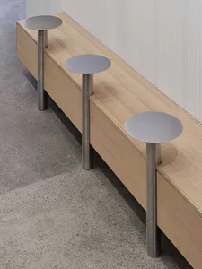 A modern wooden bench with a sleek design and silver metal legs placed on a concrete floor