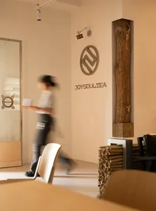 白色牆面的休閒餐廳內部，配有椅子與餐桌，有人在空間中行走
