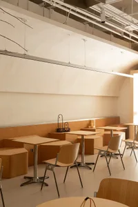 Warm and inviting restaurant space with wooden tables and chairs, natural light from windows, and a cozy atmosphere