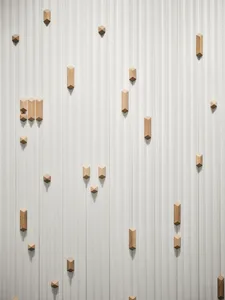 A white concrete wall with wooden blocks of various sizes and shapes attached in a creative pattern