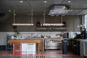Industrial kitchen with stainless steel appliances, modern dining tables, and ample lighting
