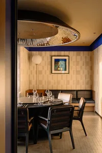 A modern dining area with a large table surrounded by chairs and a bench, giving off a sophisticated atmosphere