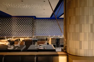 Modern restaurant interior with dining tables, chairs, and wine glasses, creating an inviting and comfortable atmosphere