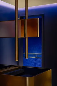A modern kitchen with a gold metal sculpture above a counter, sink area, and darkened space