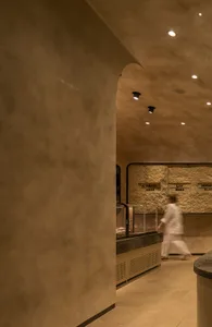 A woman walks past a kitchen counter in a casual dining restaurant with signs on the wall and a warm atmosphere