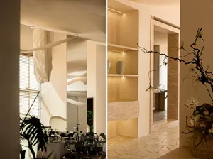 Elegant hotel lobby with potted plants, chairs, dining tables, and decorative items, set against a neutral background