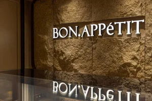 A restaurant interior with a stone wall and a sign reading Bon Appetit, creating a warm and inviting atmosphere