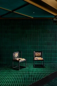 Two chairs placed at an angle in front of a green wall, creating a sense of depth and balance in a calm and inviting space