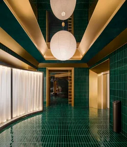 Ornate hallway with green walls, gold accents, a spiral staircase, and three white globes suspended from the ceiling