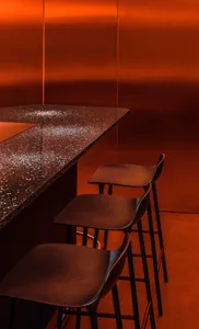 Warm and inviting orange kitchen with a countertop and three black chairs, creating a cozy seating area