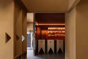 A modern bar area with a long counter featuring multiple bottles and wine glasses, set in a sophisticated atmosphere