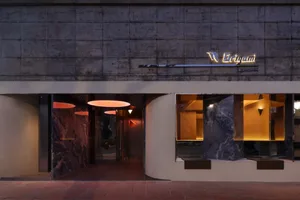 A modern building exterior at night with a stone facade, illuminated by two side lights