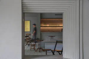 A restaurant bar area with chairs and dining tables, bottles on tables, and an inviting atmosphere