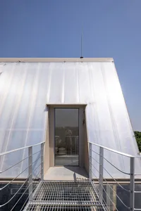 Casual outdoor living area with a metal staircase, a doorway, and two people standing near the stairs