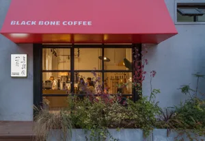 A coffee shop interior with a red awning, potted plants, and comfortable seating for customers