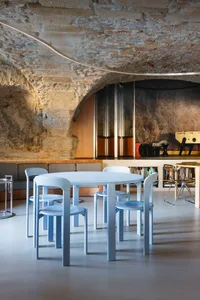 A modern dining space with a white table surrounded by four silver chairs, creating a minimalist atmosphere
