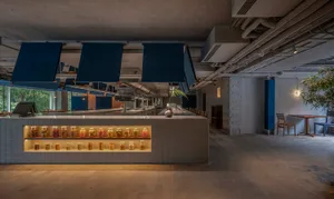 Modern restaurant kitchen with a large countertop island, chairs, bottles, and a potted plant