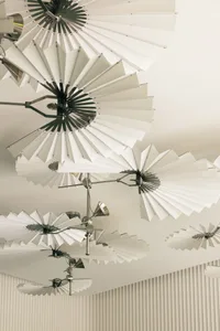 A modern ceiling design featuring white umbrellas in various shapes and sizes suspended from the ceiling